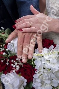 Bride and grooms hands on a flower bouquet showing their wedding rings