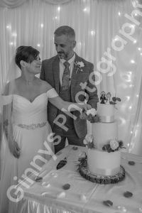 bride and groom posing their their wedding cake