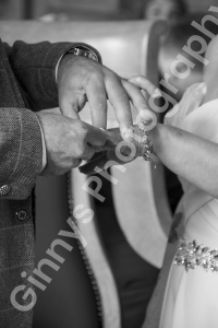 black and white image of the groom placing the ring on the brides finger