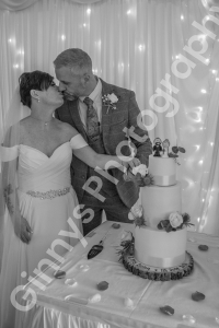 black and white image of the bride and groom cutting the wedding cake
